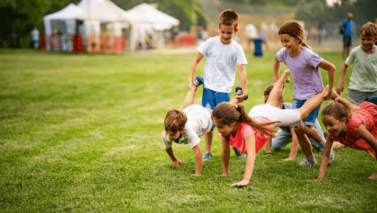 A group of children doing push ups on a grassy field.
