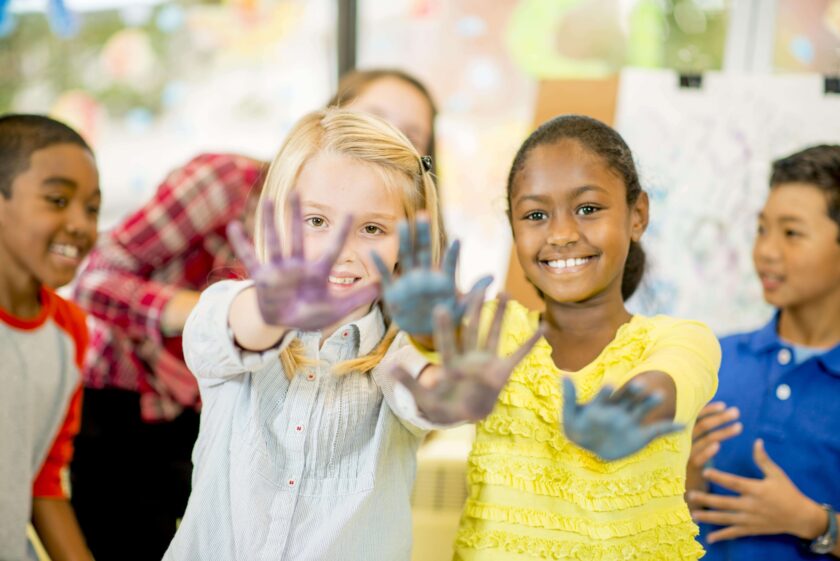 Two girls showing off their finger painted hands.